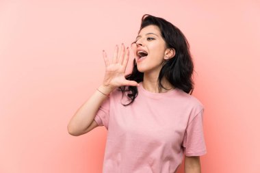 Soyutlanmış pembe arka planı olan genç bir kadın ağzı açık bağırıyor.
