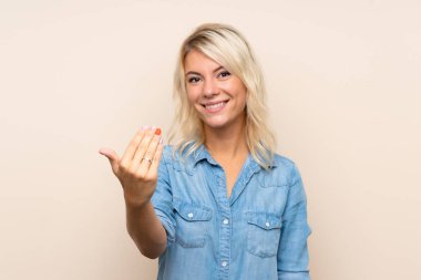 Izole arka plan üzerinde genç sarışın kadın gelmeye davet