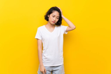 Hayal kırıklığı ve anlayış değil bir ifade ile izole sarı duvar üzerinde Asyalı genç kadın