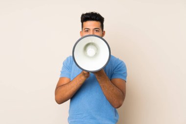 Izole arka plan üzerinde genç yakışıklı adam bir megafon ile bağırıyor