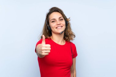 Genç sarışın kadın başparmak ile kulaklık ile çalışan