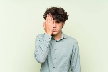 Elle bir göz kapsayan izole yeşil duvar üzerinde genç adam