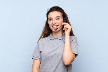 Tecrit edilmiş mavi arka planda genç esmer kız kulaklıkla çalışıyor.