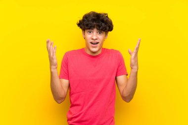 Sürpriz yüz ifadesi ile izole sarı duvar üzerinde genç adam