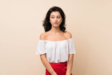 Izole arka plan üzerinde genç kadın yan görünümlü şüpheler jest yapma