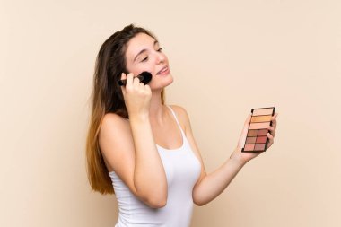 Soyutlanmış arka planda makyaj paleti olan esmer bir kız.