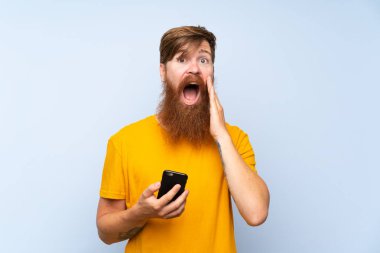 Kızıl saçlı, uzun sakallı, hareketli mavi duvarlı, şaşırmış ve şok olmuş bir yüz ifadesi olan bir adam.