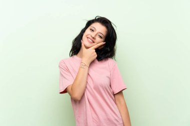 Izole yeşil arka plan üzerinde genç kadın gülümseyerek