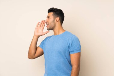 Izole arka plan üzerinde genç yakışıklı adam yanal açık ağız ile bağırarak