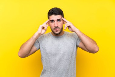 Izole sarı arka plan üzerinde genç yakışıklı adam mutsuz ve bir şey ile sinirli. Negatif yüz ifadesi
