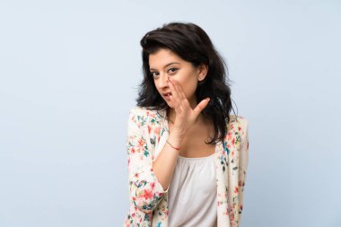 Izole mavi arka plan üzerinde genç kadın bir şey fısıldıyor