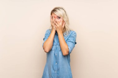 Gözleri kaplayan izole arka plan üzerinde genç sarışın kadın ve parmaklardan bakarak