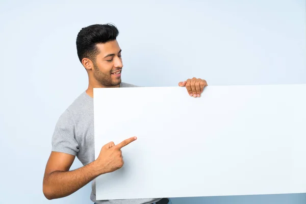 Joven Hombre Guapo Sobre Fondo Aislado Sosteniendo Cartel Blanco Vacío — Foto de Stock