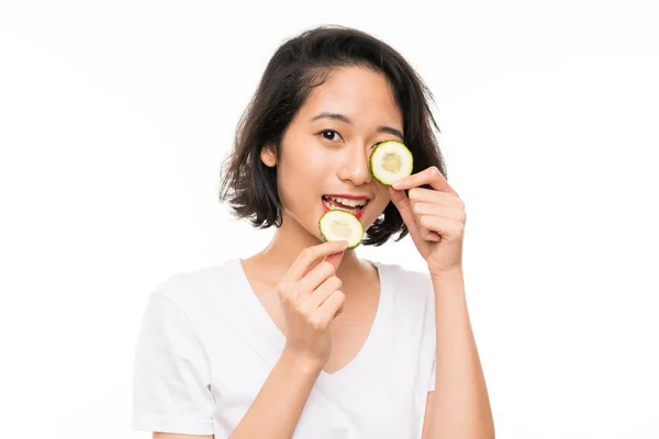 Asyalı genç bir kadın izole edilmiş arka planda elinde salatalık dilimleri tutuyor. — Stok fotoğraf