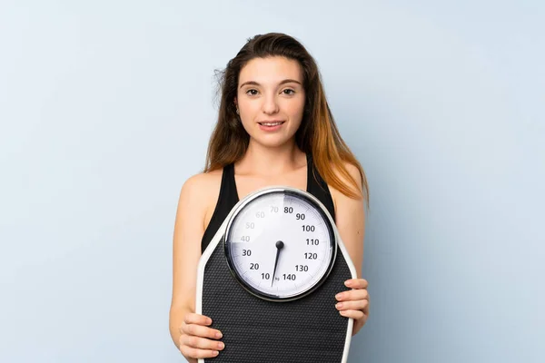 Menina morena nova com máquina de pesagem sobre backgrou isolado — Fotografia de Stock