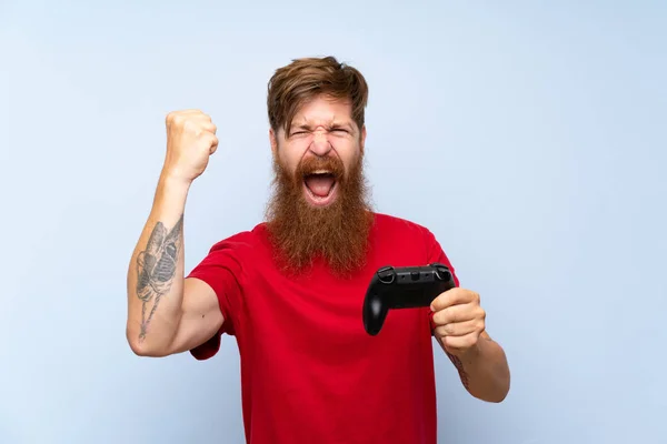 Lucky Redhead man with long beard playing with a video game controller
