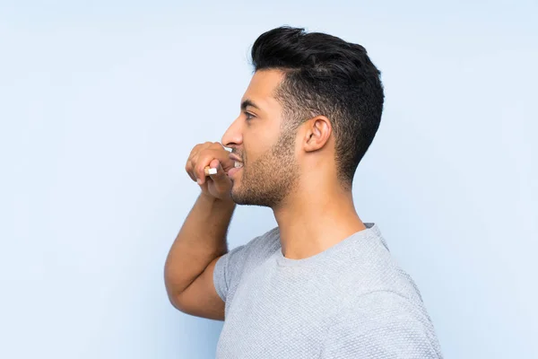 Joven afeitándose la barba sobre un fondo azul aislado — Foto de Stock