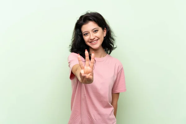 Молодая Женщина Изолированном Зеленом Фоне Счастлива Считать Троих Пальцами — стоковое фото