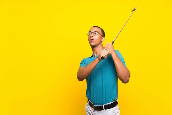 孤立した黄色の背景の上にアフロアメリカのゴルファープレーヤーの男 — ストック写真