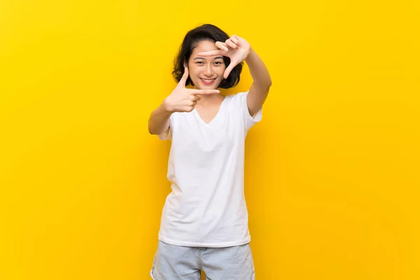 亚洲年轻女子在孤立的黄墙上聚焦脸 框架符号 — 图库照片