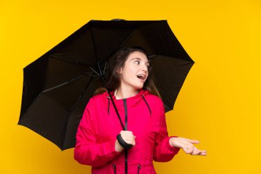 Sarı arka planda şemsiyesi olan esmer bir kız.