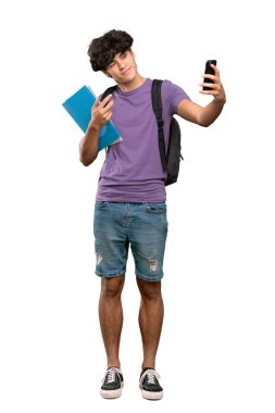 İzole beyaz arka plan üzerinde selfie yapan genç bir öğrenci nin tam uzunlukta bir fotoğrafı