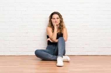 Genç sarışın kadın mutsuz ve sinirli katta oturan