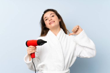 Saç kurutma makinesiyle bornozlu genç bir kadın gururlu ve kendini beğenmiş.