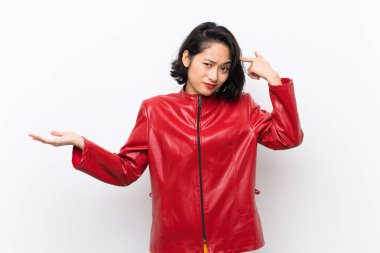 Izole beyaz arka plan üzerinde Asyalı genç kadın kafasına parmak koyarak delilik jest yapma