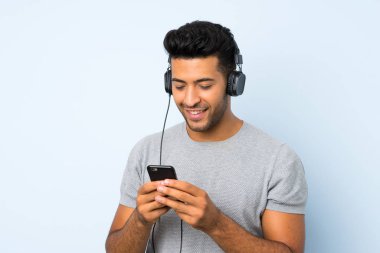 Kulaklık ile cep telefonu kullanarak izole arka plan üzerinde genç yakışıklı adam