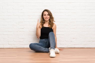 Genç sarışın kadın işaret parmağı ile işaret katta oturan harika bir fikir