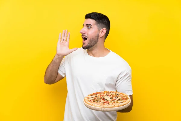 Junger Gutaussehender Mann Hält Eine Pizza Über Eine Isolierte Gelbe — Stockfoto