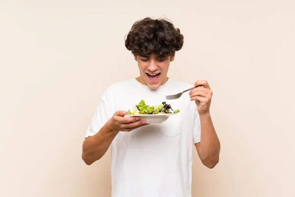 Giovane con insalata oltre isolato muro verde — Foto Stock