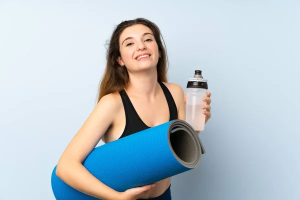 Joven morena con tapete y una botella de agua sobre un fondo aislado —  Fotos de Stock