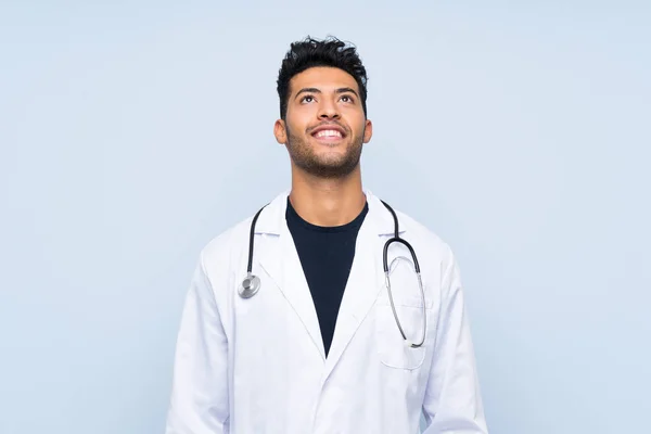 Junger Arzt Blickt Lächelnd Über Isolierte Blaue Wand — Stockfoto