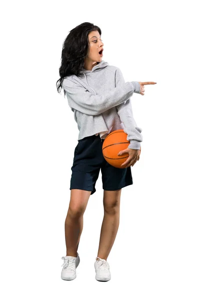 一个年轻女子打篮球的全景镜头让人惊讶 她用手指着孤独的白色背景 — 图库照片