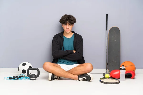 Pemuda Olahraga Duduk Lantai Sekitar Banyak Unsur Olahraga Menjaga Lengan — Stok Foto