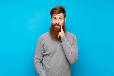 Kızıl saçlı, uzun sakallı, soyutlanmış mavi arka planı olan bir adam.