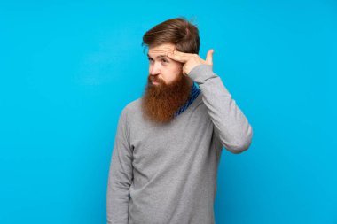 Uzun sakallı kızıl saçlı, mavi arka planda intihar jesti yapmayan bir adam.