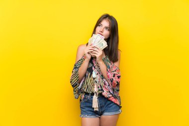 Izole sarı arka plan üzerinde renkli elbiseli Kafkas kız çok para alarak