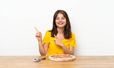 Kafkasyalı kız pizzanın kenarını işaret ediyor.