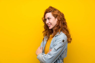 Izole sarı arka plan ayakta üzerinde Redhead kadın ve yan bakıyor