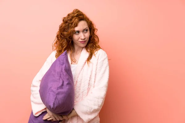 Redhead woman in dressing gown standing and thinking an idea