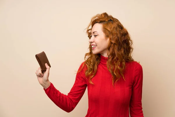 Redhead woman with turtleneck sweater holding a wallet