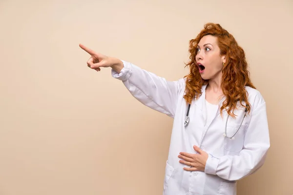 Redhead doctor woman pointing finger to the side