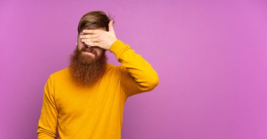 Uzun sakallı kızıl saçlı bir adam, tek başına mor arka planda, gözleri elleriyle kapatıyor. Bir şey görmek istemiyorum.