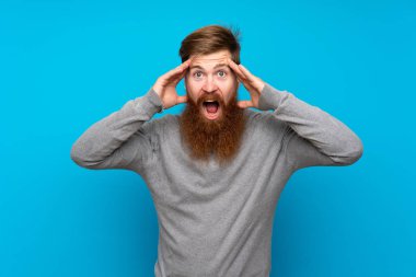 Kızıl saçlı, uzun sakallı, soyutlanmış mavi arkaplan ve sürpriz bir yüz ifadesi olan adam.