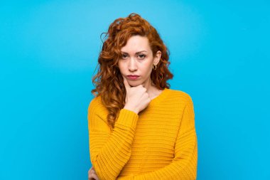 Sarı kazaklı kızıl saçlı kadın düşünüyor.