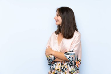 Kimonosu olan beyaz bir kız. Mavi arka planda. Yan tarafa bakıyor.