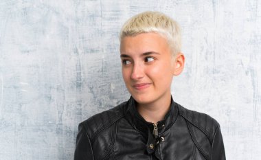 Genç kadın grunge duvar üzerinde ayakta ve yan bakıyor